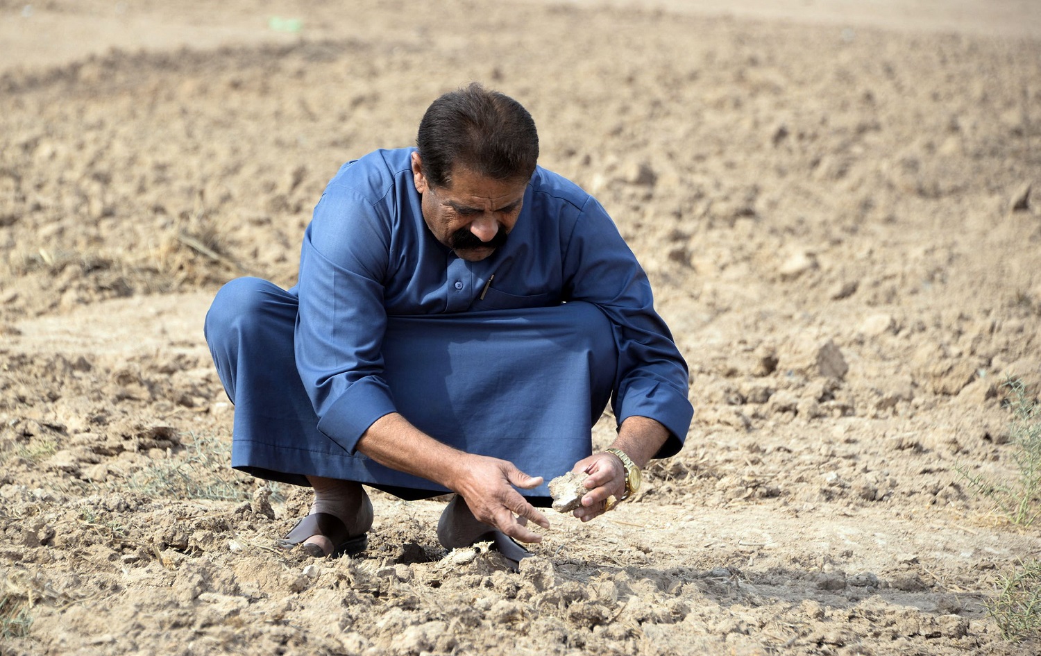 A farmer checks soil compacted by drought on a parcel of agricultural land, on the outskirts of the town of Tel Kaif, north of Mosul on October 26, 2021. Photo: Zaid al-Obeidi/AFP